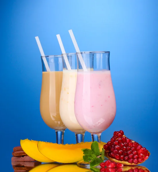 Молочні коктейлі з фруктами та шоколадом на синьому фоні — стокове фото