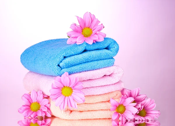 Handtücher und schöne Blumen auf rosa Hintergrund — Stockfoto