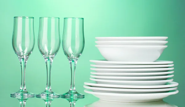 Saubere Teller und Gläser auf grünem Hintergrund — Stockfoto