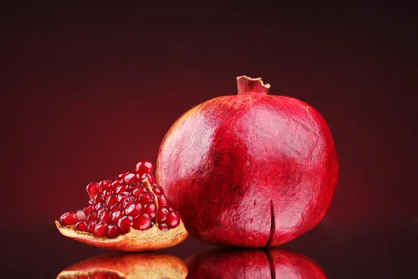 Ripe pomegranate fruit on red background — Stock Photo, Image
