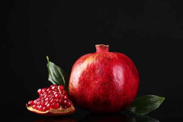Zralé granátové jablko ovoce s listy na černém pozadí — Stock fotografie