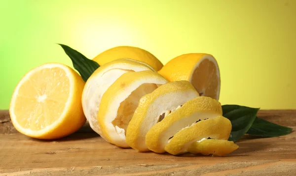 Limoni maturi con foglie su tavolo di legno su sfondo verde — Foto Stock