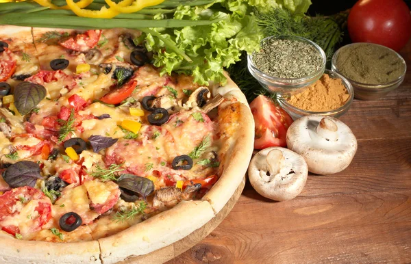 Leckere Pizza, Gemüse und Gewürze auf Holztisch — Stockfoto