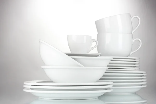 Tigelas vazias, pratos e copos sobre fundo cinza — Fotografia de Stock