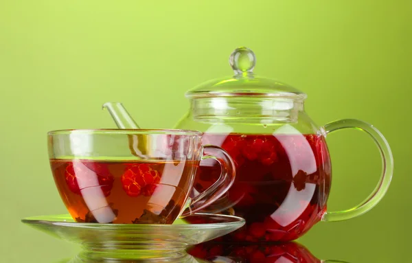 Black fruit raspberry tea in glass teapot and cup on green background — Stock Photo, Image