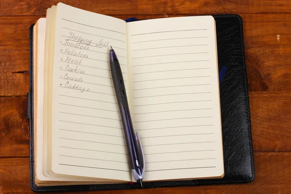 购物清单和木桌上的钢笔 — 图库照片