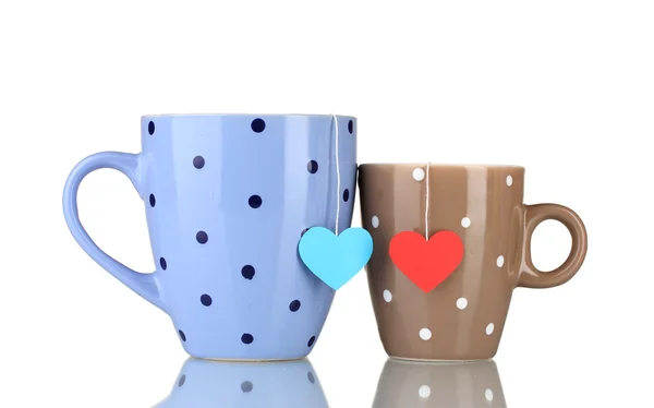 Две чашки и чайные пакетики с красной и синей сердечной маркировкой, изолированные на белке — стоковое фото