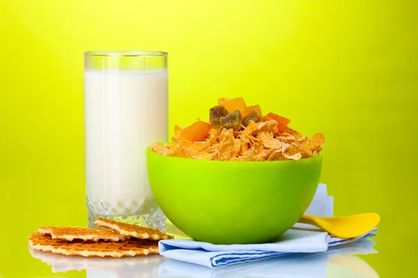 Tasty cornflakes in green bowl and glass of milk on green background — Stock Photo, Image