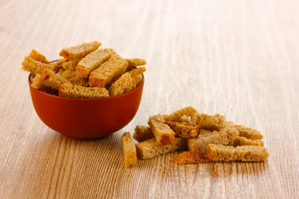 Appetizing rusks in bowl on wooden background — Stock Photo, Image