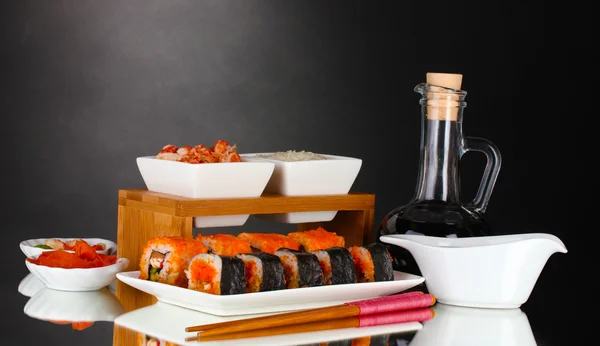 Delicioso sushi en plato, palillos, salsa de soja, pescado y camarones en gris b — Foto de Stock