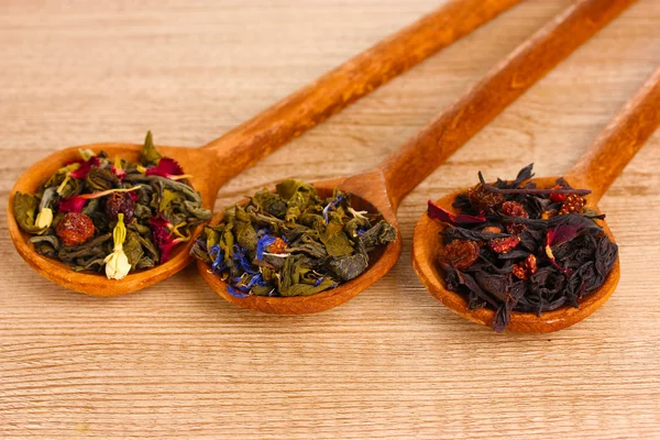 Diversi tipi di tè verde e nero secco in cucchiai su tavolo di legno — Foto Stock