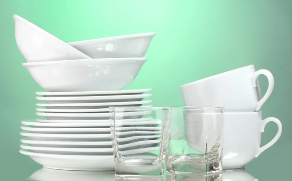 Чисті тарілки, чашка та окуляри на зеленому фоні — стокове фото
