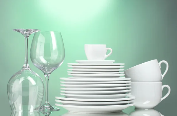 Platos, vasos y vasos limpios sobre fondo verde — Foto de Stock