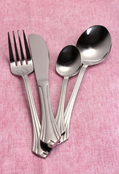 Tenedor, cuchara y cuchillo sobre un mantel rosa — Foto de Stock