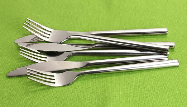 Forks and knives on a green tablecloth — Stock Photo, Image