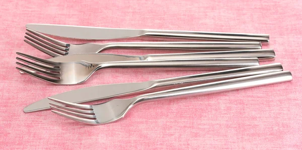 Vidličky a nože na růžové ubrus — Stock fotografie