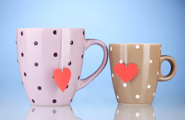 Due tazze e bustine di tè con etichetta rossa a forma di cuore su sfondo blu — Foto Stock