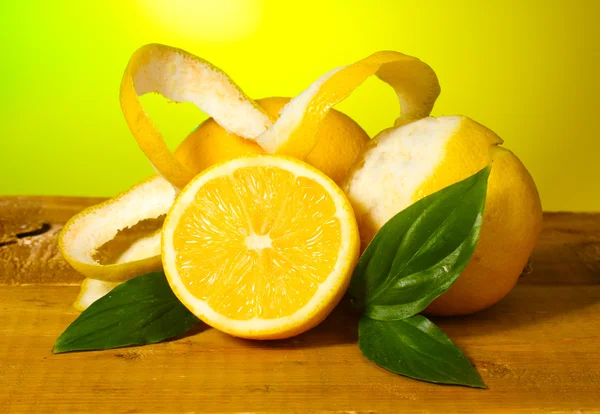 Reife Zitronen mit Blättern auf Holztisch auf grünem Hintergrund — Stockfoto