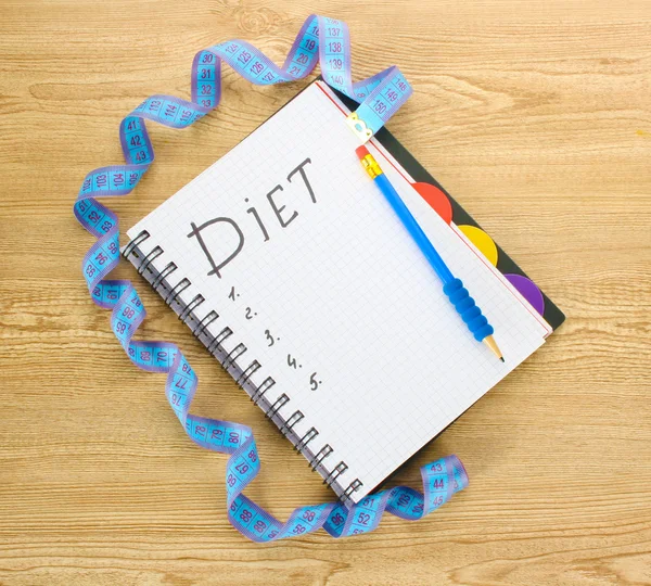 Planejamento da dieta. Caderno de fita métrica e caneta na mesa de madeira — Fotografia de Stock