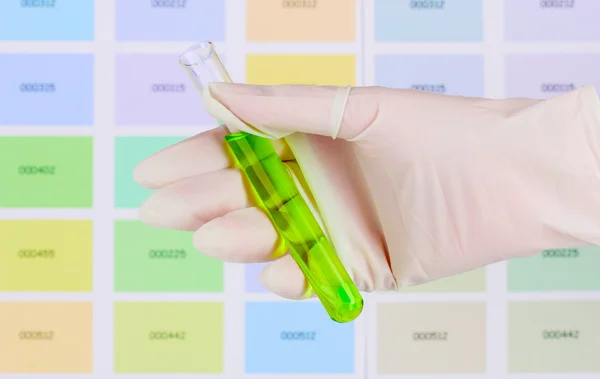 Rohr mit grüner Flüssigkeit in der Hand auf Farbmuster Hintergrund — Stockfoto