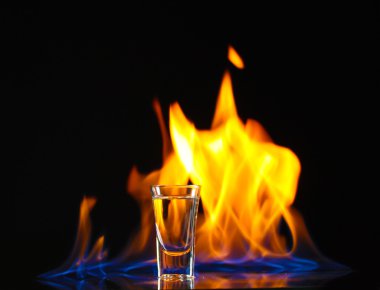 Flaming vodca on black background clipart