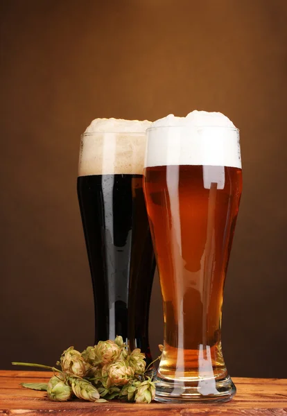 眼镜和跃点上棕色出让的木桌上的黑色和金色啤酒 — 图库照片
