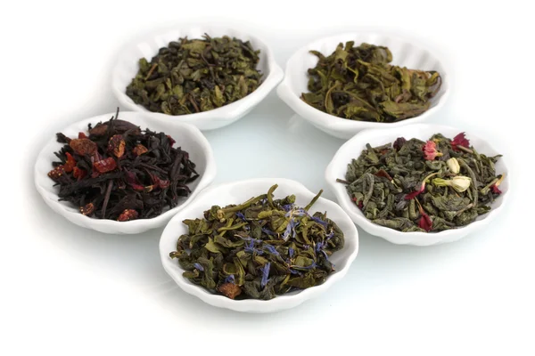 Hojas de té secas verdes y negras en platos aislados en blanco — Foto de Stock