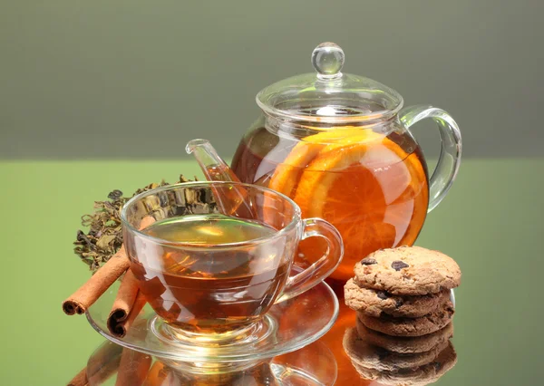 Чорний екзотичний фруктовий чай у скляному чайнику та чашку на зеленому фоні — стокове фото