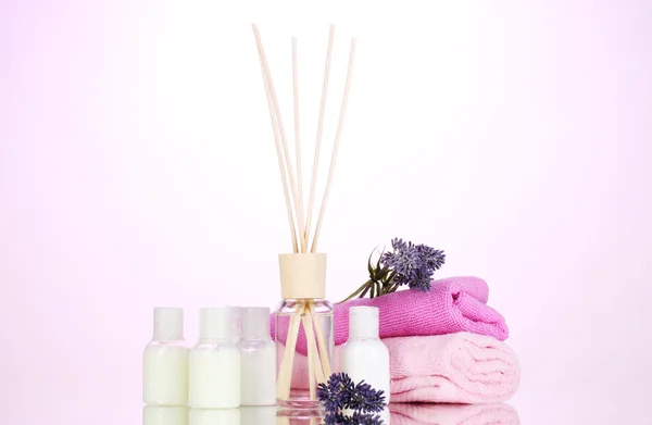 Бутылка освежителя воздуха, лаванда и полотенца на розовом фоне — стоковое фото