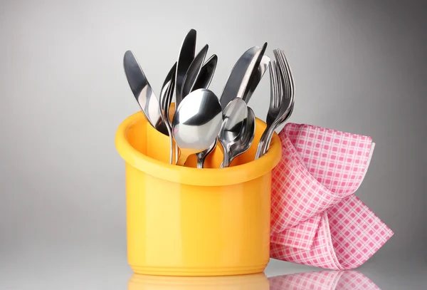 Kitchen cutlery, knives, forks and spoons in yellow stand with pink napkin — Stock Photo, Image