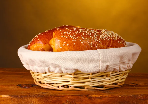 Gebakken brood in mand op houten tafel op bruine achtergrond — Stockfoto