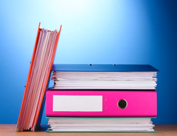 Dossiers de bureau lumineux sur table en bois sur fond bleu — Photo