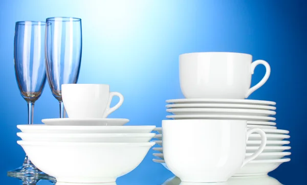 Prázdné misky, talíře, šálky a sklenice na modrém pozadí — Stock fotografie