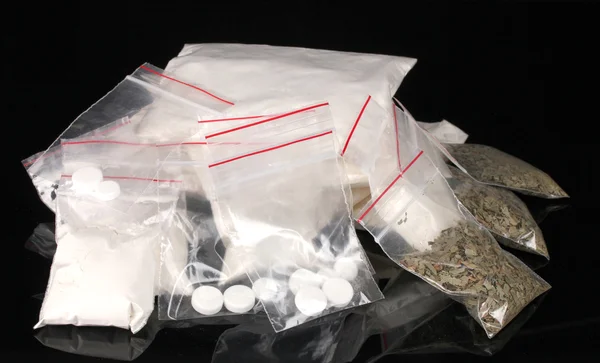 Cocaïne en marihuana in pakketten op zwarte achtergrond — Stockfoto