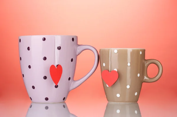 Twee kopjes en thee zakjes met rood hart-vormige label op rode achtergrond — Stockfoto
