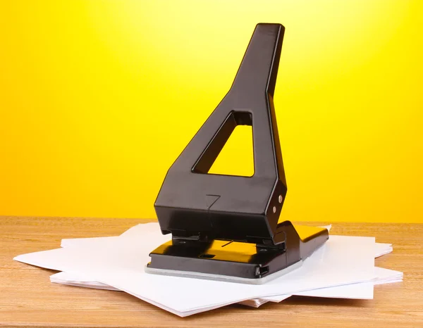 Zwarte office perforator met papier op gele achtergrond — Stockfoto