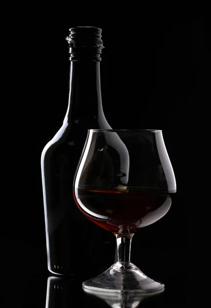Bicchiere di brandy e bottiglia su sfondo nero — Foto Stock