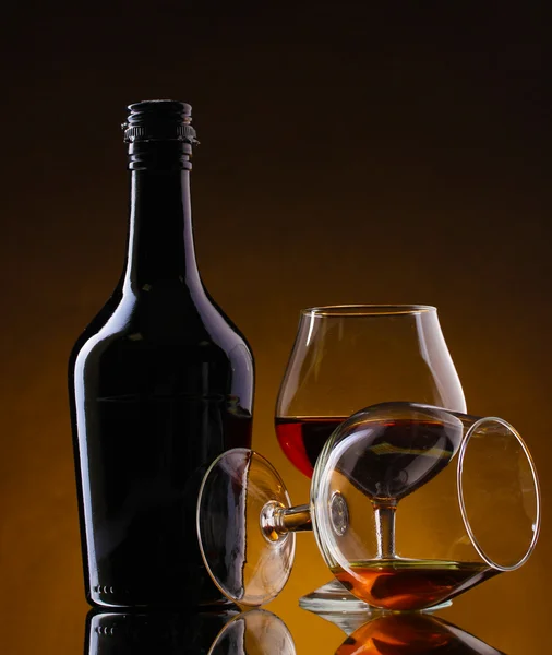 Okulary z brandy i butelka na brązowym tle — Zdjęcie stockowe