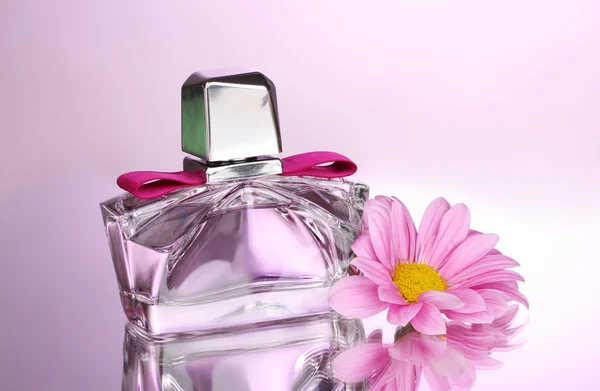 Perfume de mujer en hermosa botella y flor sobre fondo rosa — Foto de Stock