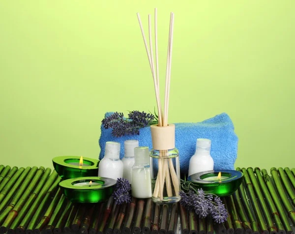 Luchtverfrisser, flessen, handdoek en kaarsen op bamboe mat op groene achtergrond — Stockfoto