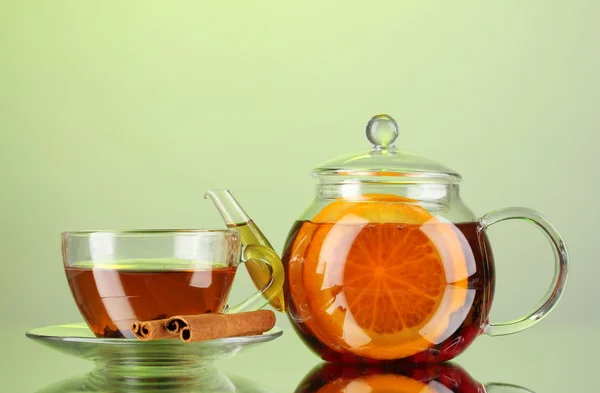 stock image Black exotic fruit tea in glass teapot and cup on green background