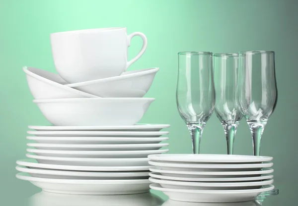 Saubere Teller, Tassen und Gläser auf grünem Hintergrund — Stockfoto