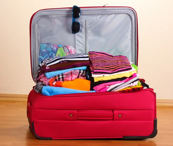 Valise ouverte rouge avec vêtements dans la chambre — Photo