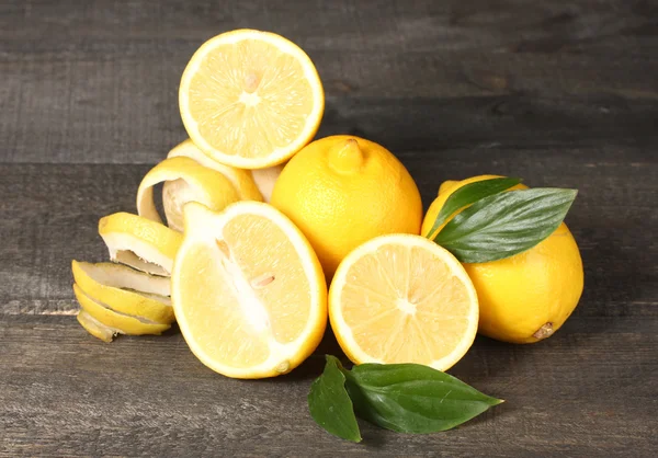 Limones maduros con hojas sobre mesa de madera —  Fotos de Stock