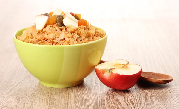 Chutné Kukuřičné vločky v misce s sušené ovoce a apple na dřevěný stůl — Stock fotografie