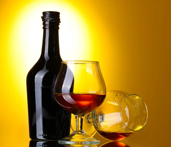 Brandy ve Sarı zemin üzerine şişe bardak — Stok fotoğraf