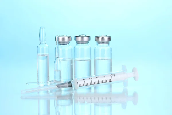 Syringe and medical ampoules on blue background — Stock Photo, Image
