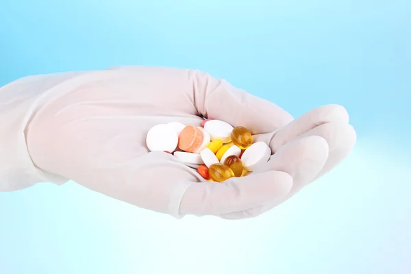 Tabletten in hand op blauwe achtergrond — Stockfoto