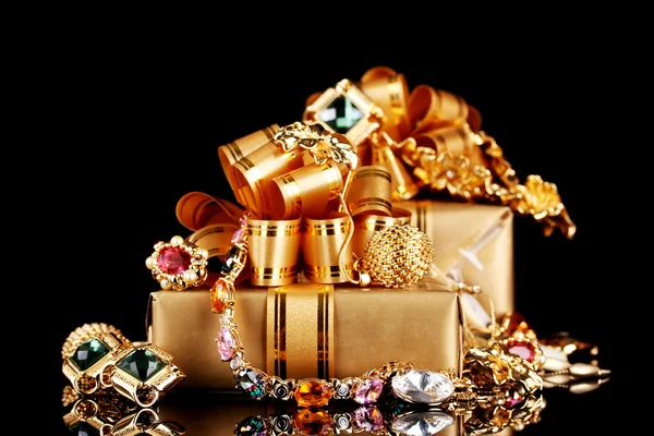Divers bijoux en or et cadeaux sur fond noir — Photo