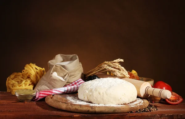 Zutaten für hausgemachte Pasta auf Holztisch auf braunem Hintergrund — Stockfoto
